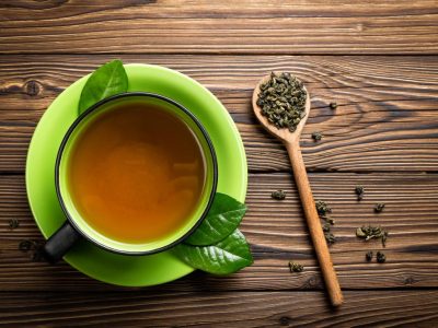 green-tea-in-cup-with-tea-leaves-on-wooden-spoon